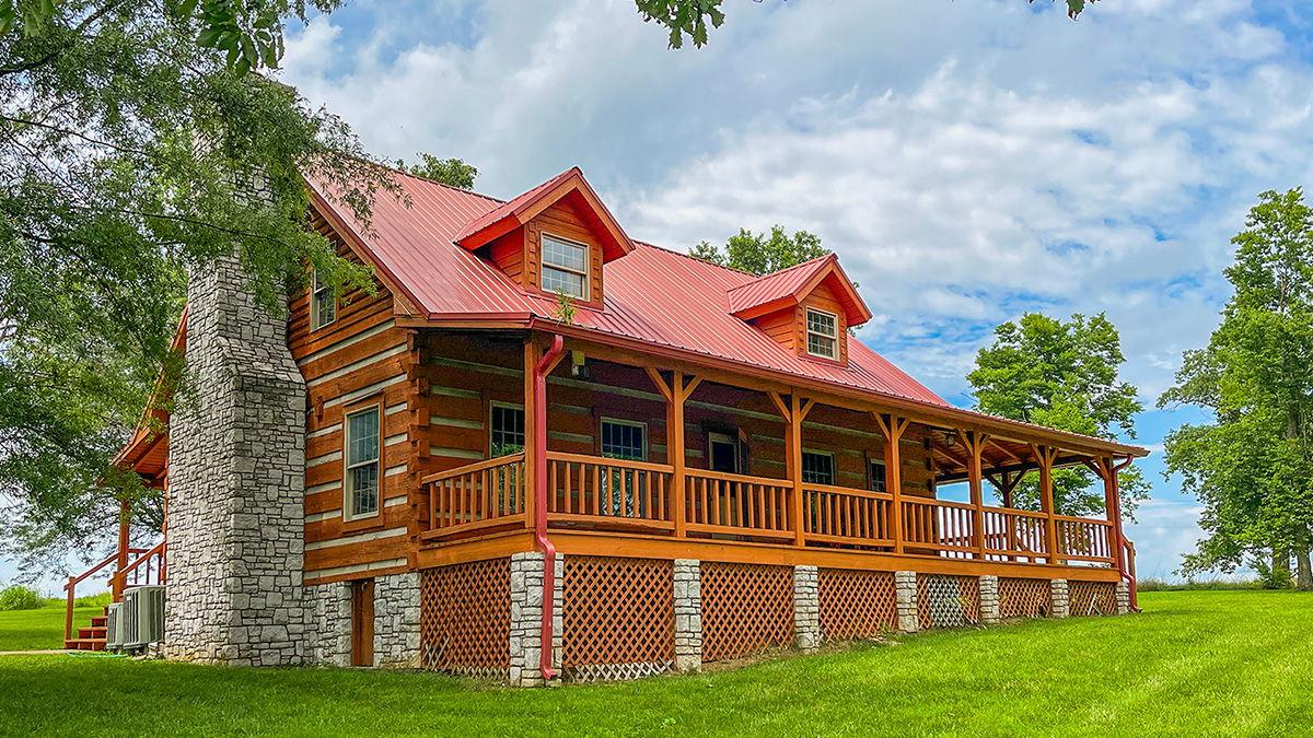 The Serene Cabin exterior with a red roof and wraparound porch